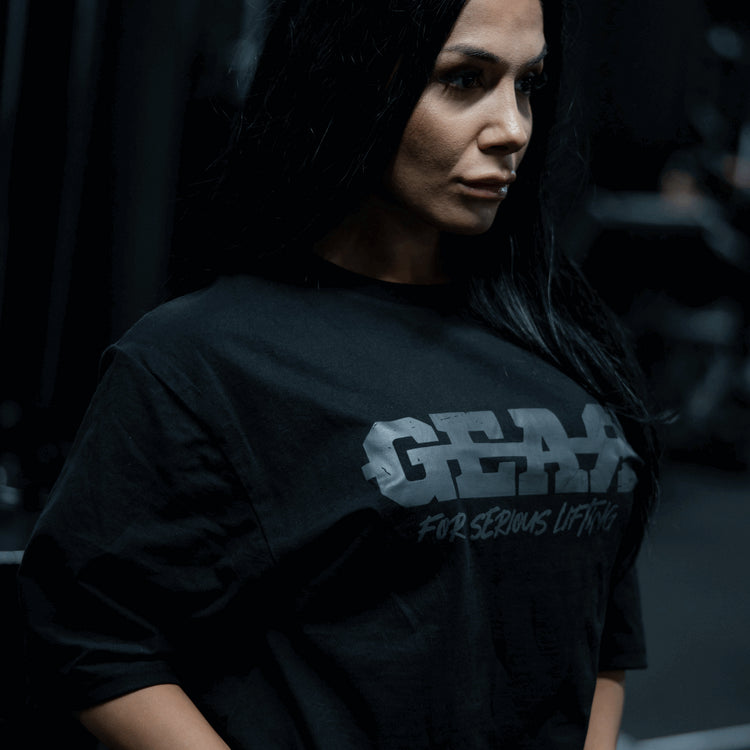 Naisten musta GEAR-treenipaita – 'For Serious Lifting' -teksti edessä, oversized salipaita urheilullisella naisella kuntosalilla